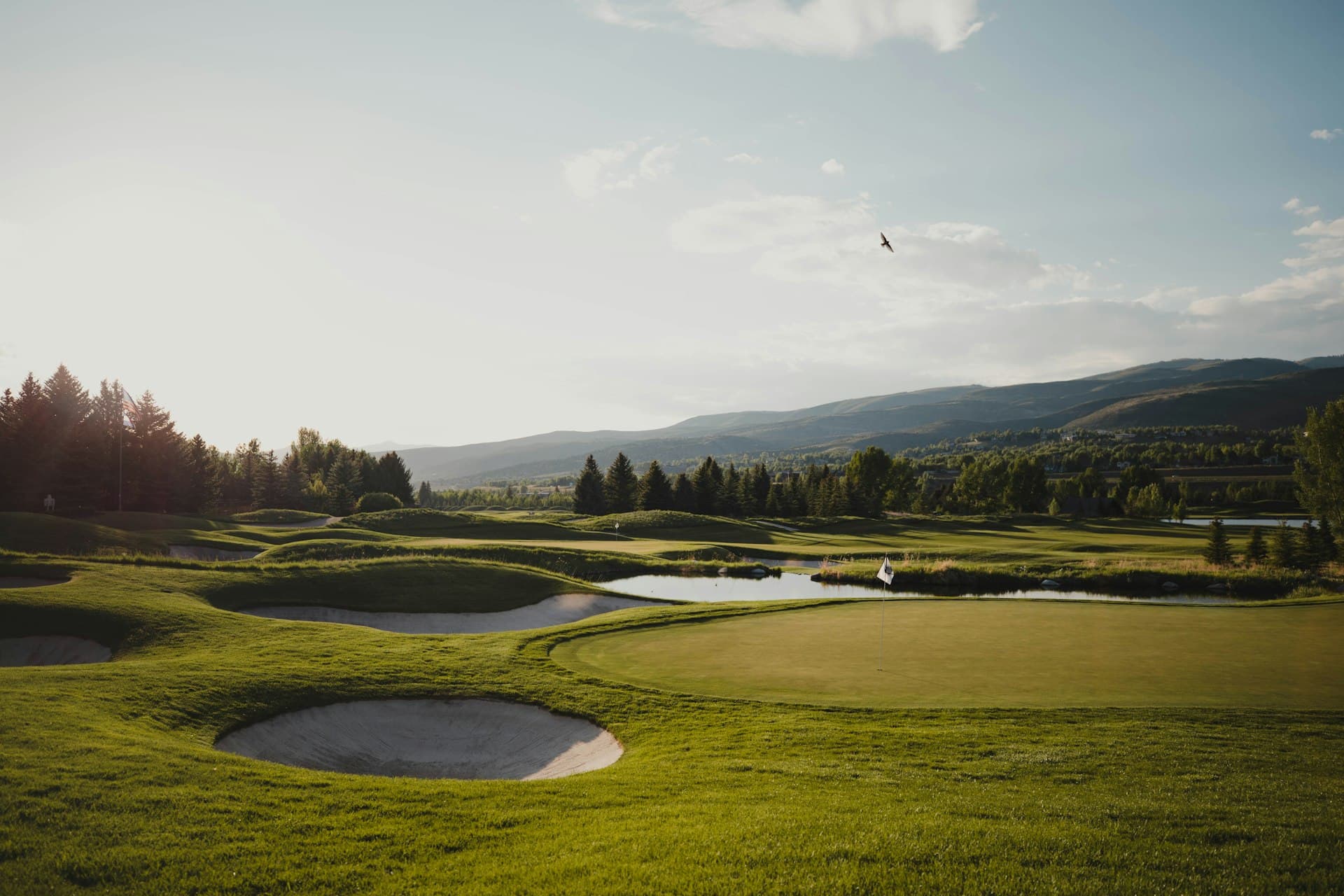 Sweeping golf course fairway with water and mountains